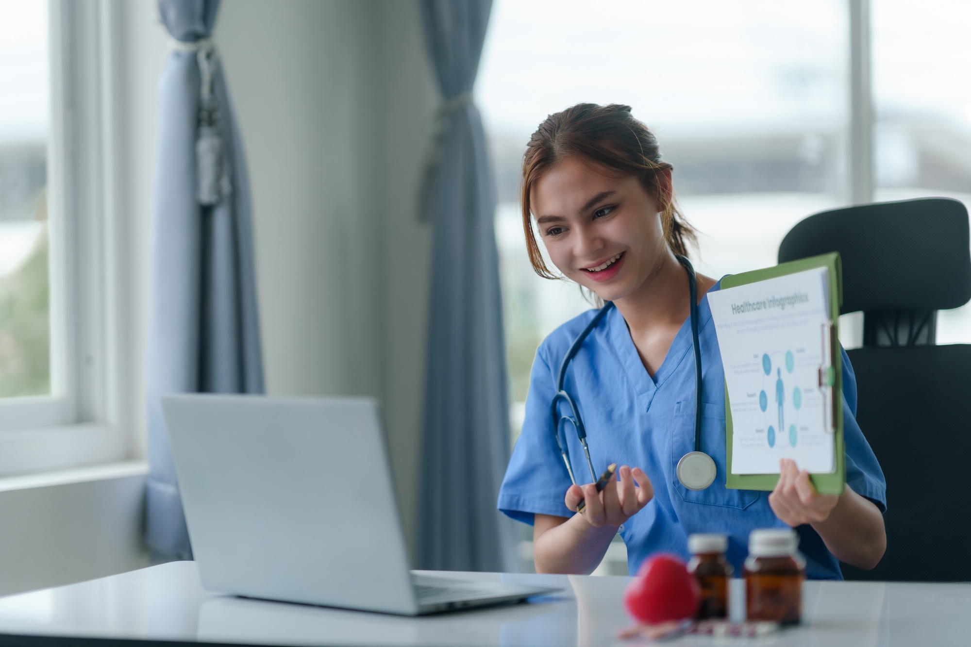 Doctor or nurse consulting with patient online using laptop computer in hospital.